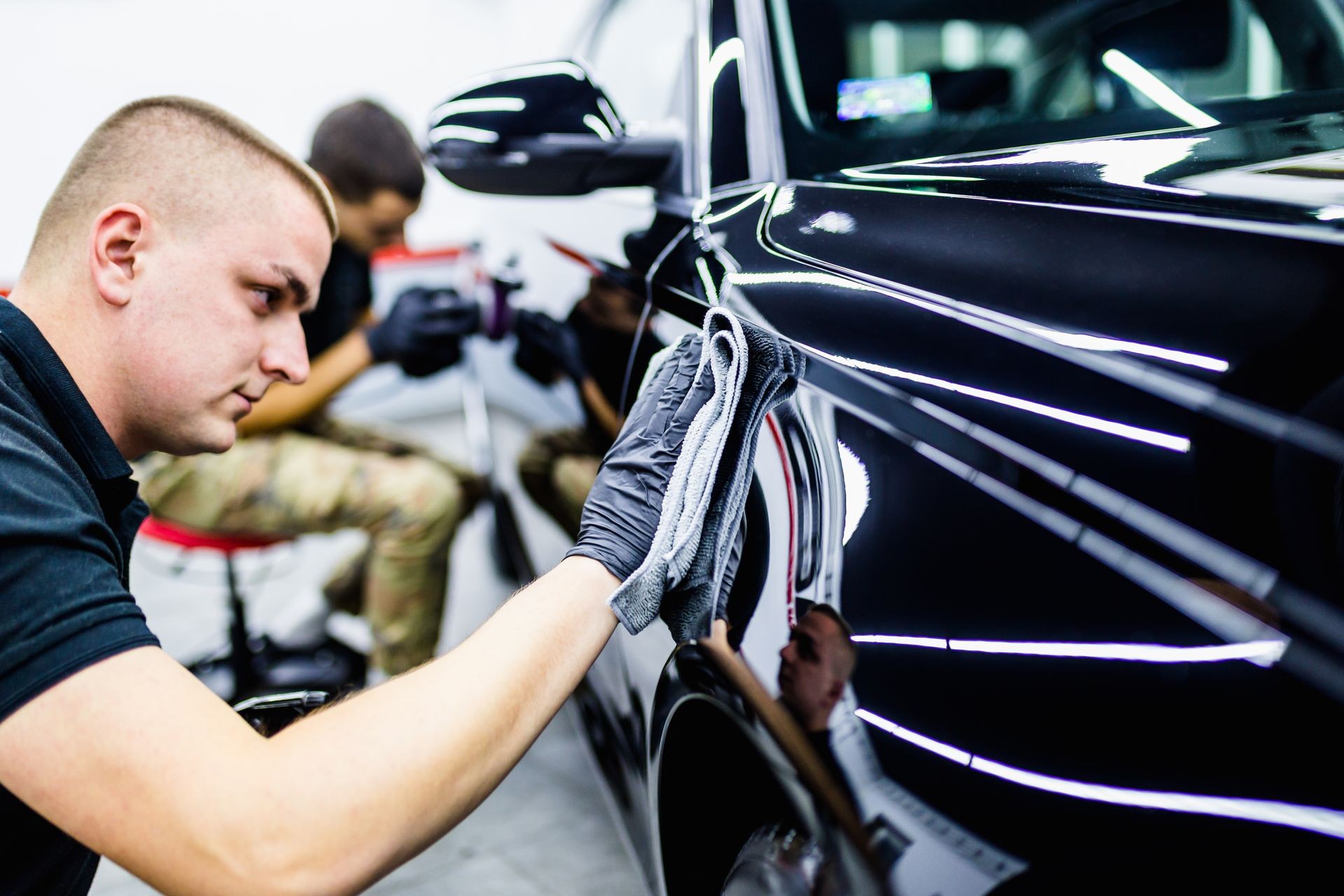 A man cleaning car with cloth, car detailing (or valeting) concept. Selective focus. 